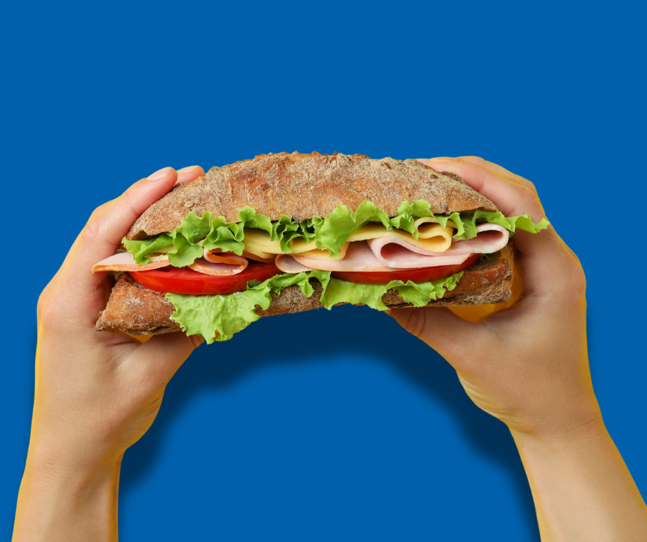 hands holding a sub sandwich on blue background
