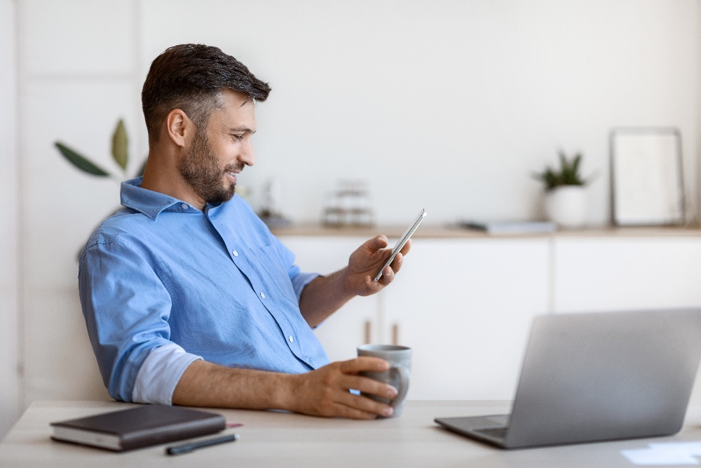 handsome-male-freelancer-using-smartphone-and-havi-2022-12-16-06-40-50-utc-1