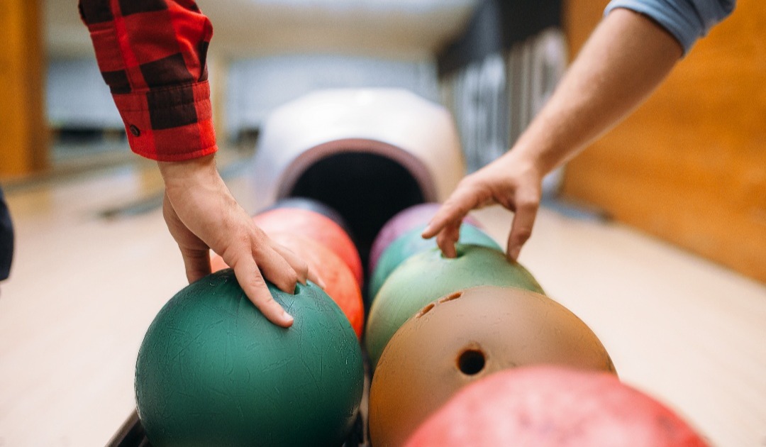 two-male-bowlers-takes-balls-from-feeder-2021-08-26-16-26-46-utc-1